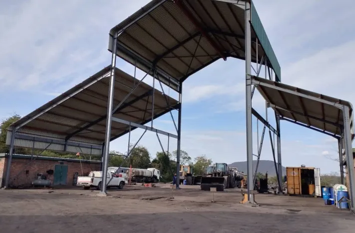 Multi-bay steel garage shed at Gwanda with vehicles parked beyond